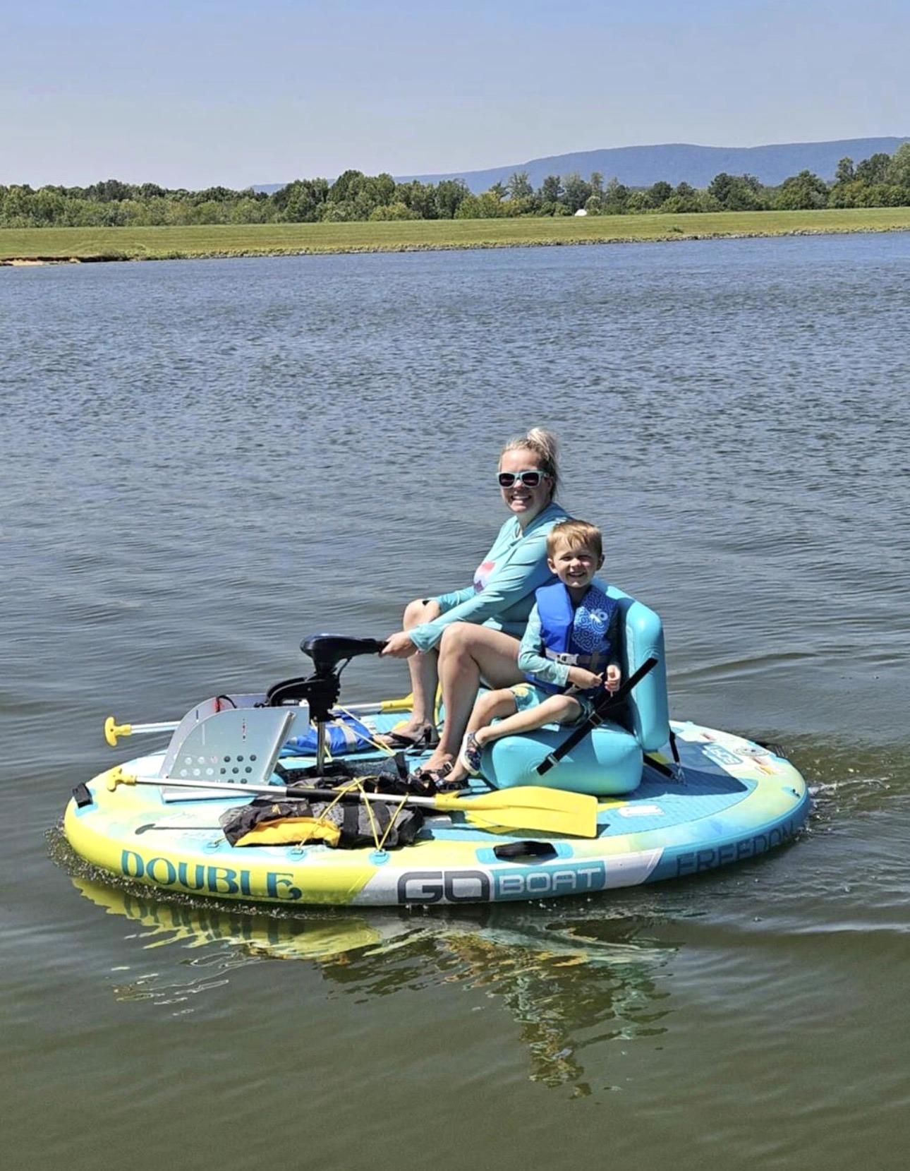 A mom and her young son smiling aboard a colorful round Double GoBoat on a bright sunny day